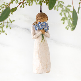 Figure in cream dress, holding large bouquet of blue forget-me-not flowers up to face. Hook and loop affixed to figure's head