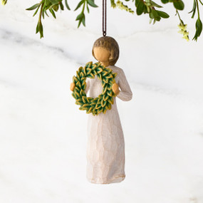 Figure in cream dress, holding green wreath of magnolia leaves in front of her. Hook and loop affixed to figure's head