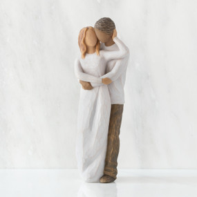 Front view of couple, standing with arms around each other. Woman has lighter skin and hair; man has darker skin and hair.