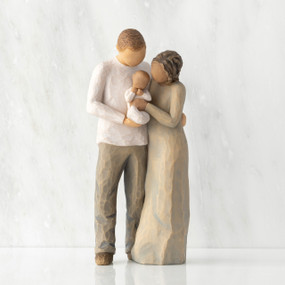 Front view of standing couple, woman has darker skin and hair; man has lighter skin and hair, holding a baby between them.