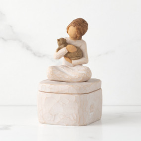Front: cream square resin box with lid, 3-D figure of seated girl holding cat atop lid