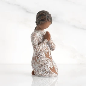 Front: Kneeling figure with darker skin, hands in position of prayer or meditation in cream dress carved with icons of nature
