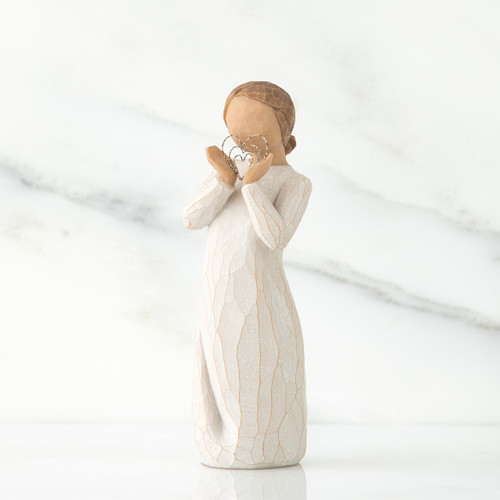 Small girl figurine faceless wearing white dress and holding silver heart figurine