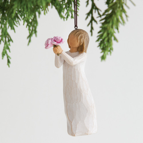 Front view of woman ornament with short brown hair, holding out a bouquet of pink flowers. Brown string attached to top of ornament