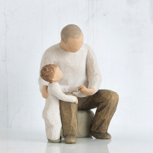 Faceless dad figurine sitting on rock holding little boy figurine's hand