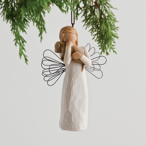 Faceless girl figurine wearing white dress holding brown puppy - wire wings - background is green branches