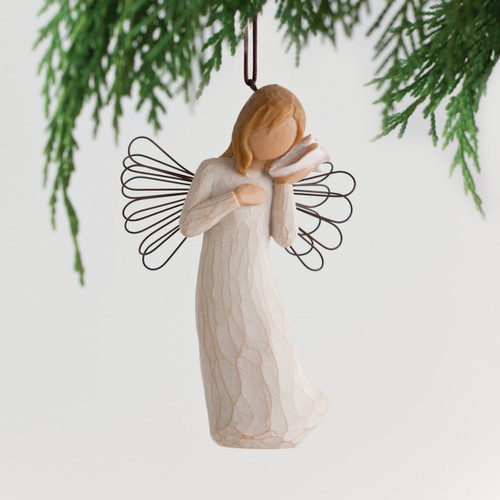 Faceless angel figurine wearing white dress, holding seashell to her ear, black wire wings - background is white with green branches on top