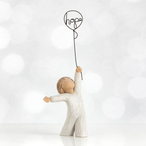 Small child faceless figurine in white standing holding black wire 'hope' balloon up with one hand
