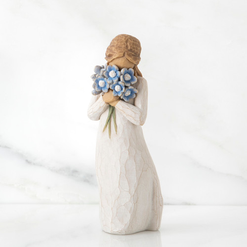 Front view of woman with tied back brown hair holding a cluster of blue flowers up to her face
