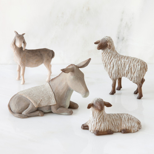 Light grey donkey figurine laying down surrounded by three sheep standing figurines