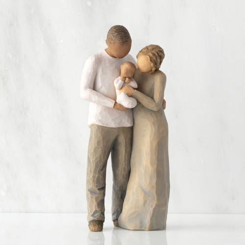 Front view of standing couple, woman has lighter skin and hair; man has darker skin and hair, holding a baby between them.