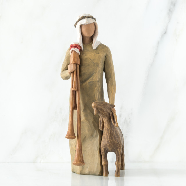 Wise man figurine standing in light brown attire with white headpiece, brown sheep at his feet
