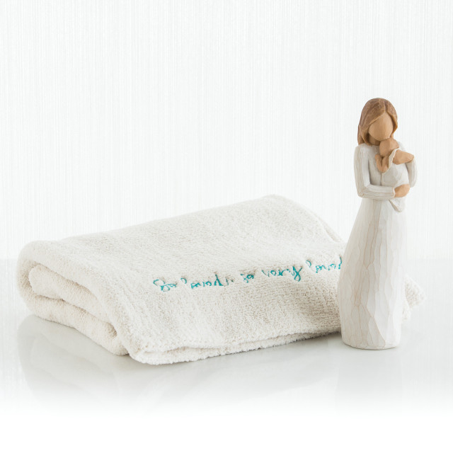 Brown haired woman figurine wearing white holding baby - next to white towel