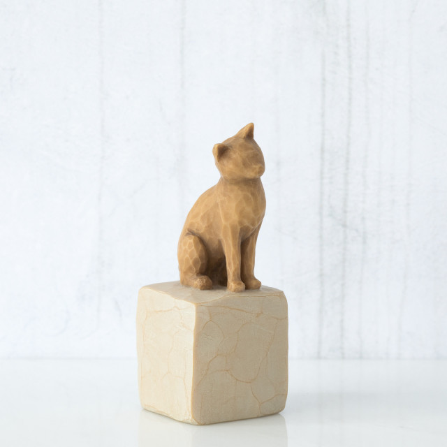Golden cat figurine sitting on white rock