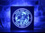 A Skeleton Astronaut LED sign featuring a skeleton named Skully in an astronaut suit, saluting. The sign has a vibrant blue glow, customizable text, and is set against a brick wall, with a durable wood frame and black acrylic front