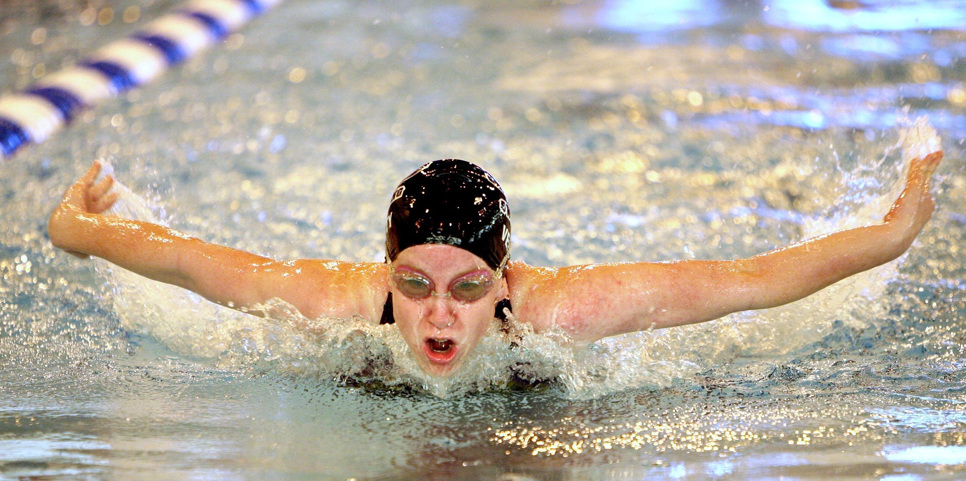 A woman is swimming in a pool wearing swim goggles