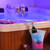 Romantic hot tub scene with rose petals, two champagne flutes, wine bottle in illuminated ice bucket.