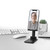 Adjustable black phone stand on office desk with smartphone, keyboard, mouse, and notebook.