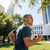 Wireless grey earbuds worn outdoors by man jogging in blue t-shirt
