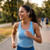 Woman running outdoors wearing blue sports top and true wireless earbuds