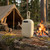 Portable beige Bluetooth speaker on a log, campsite and campfire in background