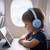 Child wearing light blue headphones watching a cartoon on a tablet during flight