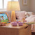 Children’s bedside table with pink headphones, lamp, tablet, and toys in softly lit bedroom