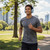 Man wearing grey sports t-shirt and blue headphones jogging in city park