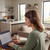 Woman wearing brown wireless headphones working on a laptop at home desk