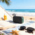 Portable black Bluetooth speaker on beach towel near sunglasses and sun lotion