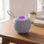 Blue wireless portable speaker with LED light on top, placed on a wooden table