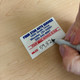 Mileage being written on a custom oil change reminder sticker with a Sharpie marker