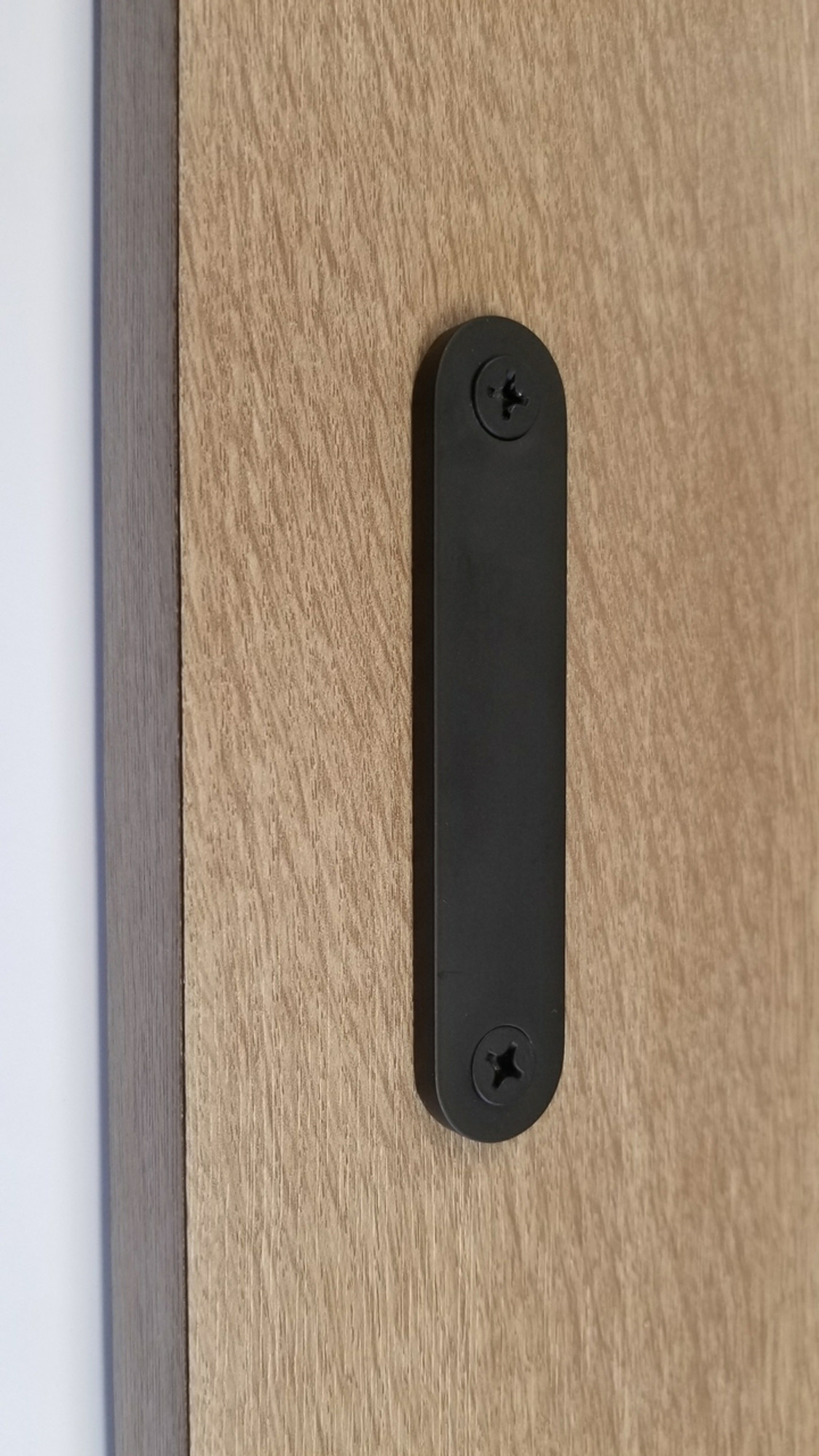 Low-Profile Back-to-Back Sliding  Door Pull (Black Powder Stainless Steel Finish) mockup on wood door