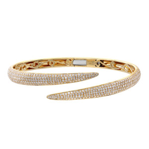 An image of a Rachel Koen women's bracelet with diamonds, showcased on a plain background. The bracelet is positioned horizontally across the center of the frame with a slight tilt, allowing a clear view of its intricate details. The perspective is a close-up, capturing the bracelet's sparkle and the fine craftsmanship of the yellow gold setting from a top-down angle. The round cut diamonds are encrusted along the top surface of the bracelet, which is open-ended with the two tips curving away from each other.