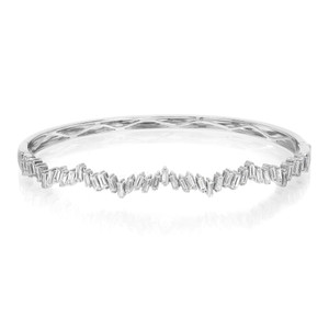 An image of a Rachel Koen women's bracelet with diamonds, presented in a front-facing view centered horizontally on a white background. The bracelet features a series of sparkling, baguette-cut diamonds set in a continuous zig zag line along the band. The diamonds are arranged edge-to-edge around the entirety of the bracelet, which is shown in a slight perspective that gives depth to the image, with the front of the bracelet appearing closer and the sides gently receding. The bracelet is made in highly polished white gold, reflecting light and emphasizing the clarity and shine of the diamonds.