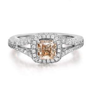 An image of a Rachel Koen women's cocktail ring with diamonds, showcasing a central cushion-cut champagne diamond in a prong setting, surrounded by a halo of smaller round-cut diamonds in white gold. The band is also adorned with diamonds and is captured in a close-up front view at eye level, with a focus on the details and craftsmanship of the ring. The background is a neutral, soft white, emphasizing the sparkle and design of the jewelry piece.