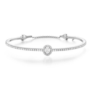 An image of a Messika women's Skinny Glam'Azone bangle 18k white gold bracelet with diamonds, displayed on a white background. The bracelet is positioned horizontally across the center of the frame, with a slight curve to show its flexibility. It features a central diamond surrounded by a halo of smaller diamonds, which is also the focus of the bracelet, with the rest of the band encrusted with evenly spaced diamonds. The perspective is straight-on and the distance is such that the entire bracelet is in focus, providing a clear view of the craftsmanship and design.