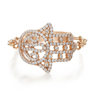 An image of a Messika women's Faith ring with diamonds, featuring a close-up view on a white background. The ring is angled to display the intricate design and the sparkling diamonds, which are set in a rose gold band. The design suggests a lattice pattern with varying sizes of round-cut diamonds, offering a view that highlights both the overall shape of the ring and the detailed craftsmanship. The ring is positioned to showcase the top view, providing a clear sense of its ornate pattern and the luxurious appearance of the stones.