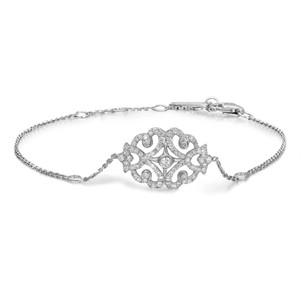 An image of a women's Messika Sultane Diamond chain 18k white gold bracelet with diamonds displayed against a white background. The bracelet is laid out straight, with the central decorative element facing upwards. The central motif, adorned with multiple sparkling diamonds, has an intricate, symmetrical, openwork design resembling a stylized flower or mandala. The image is taken from a top-down angle, showing the piece in full, with a clear view of the clasp mechanism on the right. The bracelet appears to be at a medium distance from the viewer, allowing for detailed observation of the diamonds and the overall craftsmanship.