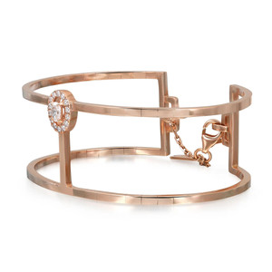 An image of a Messika women's Manch Glam'Azone 2 row bracelet with diamonds, displayed against a white background. The bracelet is made of rose gold and features a circular band with a unique open design. The main focal point is a large diamond set within a halo of smaller diamonds, positioned off-center to the right. The bracelet is shown at a slight angle, revealing the clasp detail and the brand's signature design elements. The perspective is a close-up, providing a clear view of the bracelet's craftsmanship and the sparkle of the diamonds.