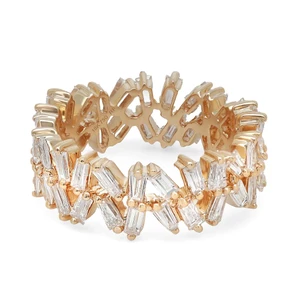 An image of a Rachel Koen women's ring with diamonds, showcasing a yellow gold band with an intricate cut-out design. The ring is adorned with multiple baguette-cut diamonds arranged in a staggered, alternating pattern, giving the appearance of shimmering leaves or feathers. The photo is taken from a top-down angle, displaying the ring's full circle, and is captured from a close, but not macro, distance, allowing for clear visibility of the diamond's shapes and the ring's detailed band design. The lighting highlights the sparkle of the diamonds and the warm hue of the gold.