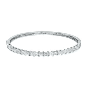 An image of a Rachel Koen women's bangle bracelet with diamonds, displayed in a close-up front view on a neutral background. The bracelet is positioned horizontally across the frame with a slight angle, showcasing a row of sparkling emerald cut diamonds set in a polished white gold. The focus is on the intricate details and craftsmanship, with the diamonds catching the light, providing a clear view of the bracelet's luxurious design.