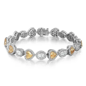 An image of a Rachel Koen women's bracelet with diamonds, displayed in a straight horizontal line at a close-up angle to show detail. The bracelet features alternating oval-cut white and heart shape yellow diamonds, each surrounded by smaller round-cut diamonds in halo setting, set in white gold metal with intricate filigree links. The clasp is visible on the left, indicating a front-facing view with the bracelet extending from the foreground to the background. The diamonds glisten against the neutral, light background, highlighting the bracelet's elegance and craftsmanship.