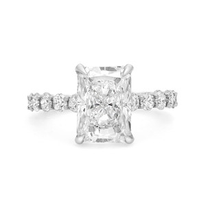 An image of a Rachel Koen brand women's engagement ring with lab grown diamonds, showcasing a prominent center stone with a rectangular cut, set in a four-prong setting. The ring is viewed from a front-facing angle, highlighting the band which is adorned with smaller round-cut diamonds on either side on the band in white gold. The image is a close-up, providing a clear view of the ring's details and craftsmanship.