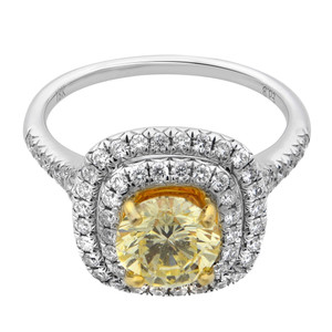 An image of a Rachel Koen women's engagement ring with diamonds, positioned front and center against a white background. The ring features a prominent yellow round cut diamond surrounded by a halo of smaller white round-cut diamonds. The band is made of polished white gold, and the view is a close-up, top-down angle that highlights the intricate details and brilliance of the diamonds. The ring occupies a significant portion of the frame, providing a clear and detailed view of the jewelry piece.