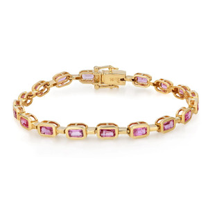 An image of a Rachel Koen women's bracelet with pink sapphire gemstones. The bracelet is displayed in a straight line from a top-down perspective, showcasing its entire length. It features a series of rectangular gold links with pink gemstones set in a bezel setting in yellow gold. The clasp is visible and appears to be a box-type mechanism, matching the bracelet's gold tone. The gemstones are evenly spaced, offering a consistent pattern. The image is taken from a close distance, providing a clear view of the bracelet's design and the facets of the gemstones.