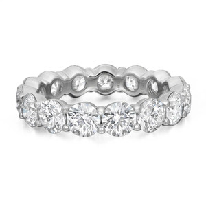 An image of a Rachel Koen brand women's eternity band ring with lab grown diamonds, displayed at a diagonal angle that reveals the full circle of the band. The ring features large, round-cut diamonds evenly spaced and encased in prong settings in white gold, with the band itself appearing polished and smooth. The image is a close-up, offering a clear view of the diamonds' facets and the ring's intricate design.