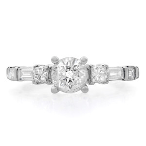 An image of a Rachel Koen brand women's engagement ring with diamonds, displayed in a close-up front view. The ring features a prominent central round-cut diamond, flanked on either side by smaller square-cut diamonds, all set in a polished white gold band. The angle of the photo provides a clear view of the ring's design and diamond arrangement.