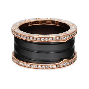 An image of a Bvlgari B.Zero1 unisex adult ring with diamonds, showcased at a slight angle to display the top and side views. The ring features a distinctive design with four  stacked black ceramic bands interspersed with rose gold bands, the latter embellished with sparkling diamonds. The perspective of the image provides a close-up view, highlighting the detailed craftsmanship and the contrast between the dark bands and the brilliance of the diamonds.