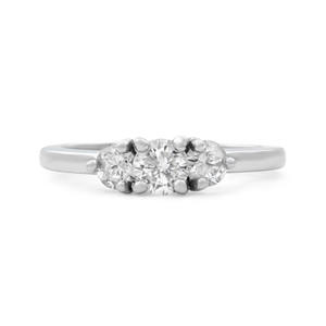 An image of a Rachel Koen brand women's engagement ring with diamonds, viewed from a front angle that showcases the three main stones in focus. The ring is centered horizontally in the frame, set against a white background, and the distance is close enough to highlight the diamonds' cut and the ring's band details. The ring appears to have a polished 14k white gold band with a trio of round-cut diamonds in a prong setting, with the central diamond being slightly larger than the two flanking it.